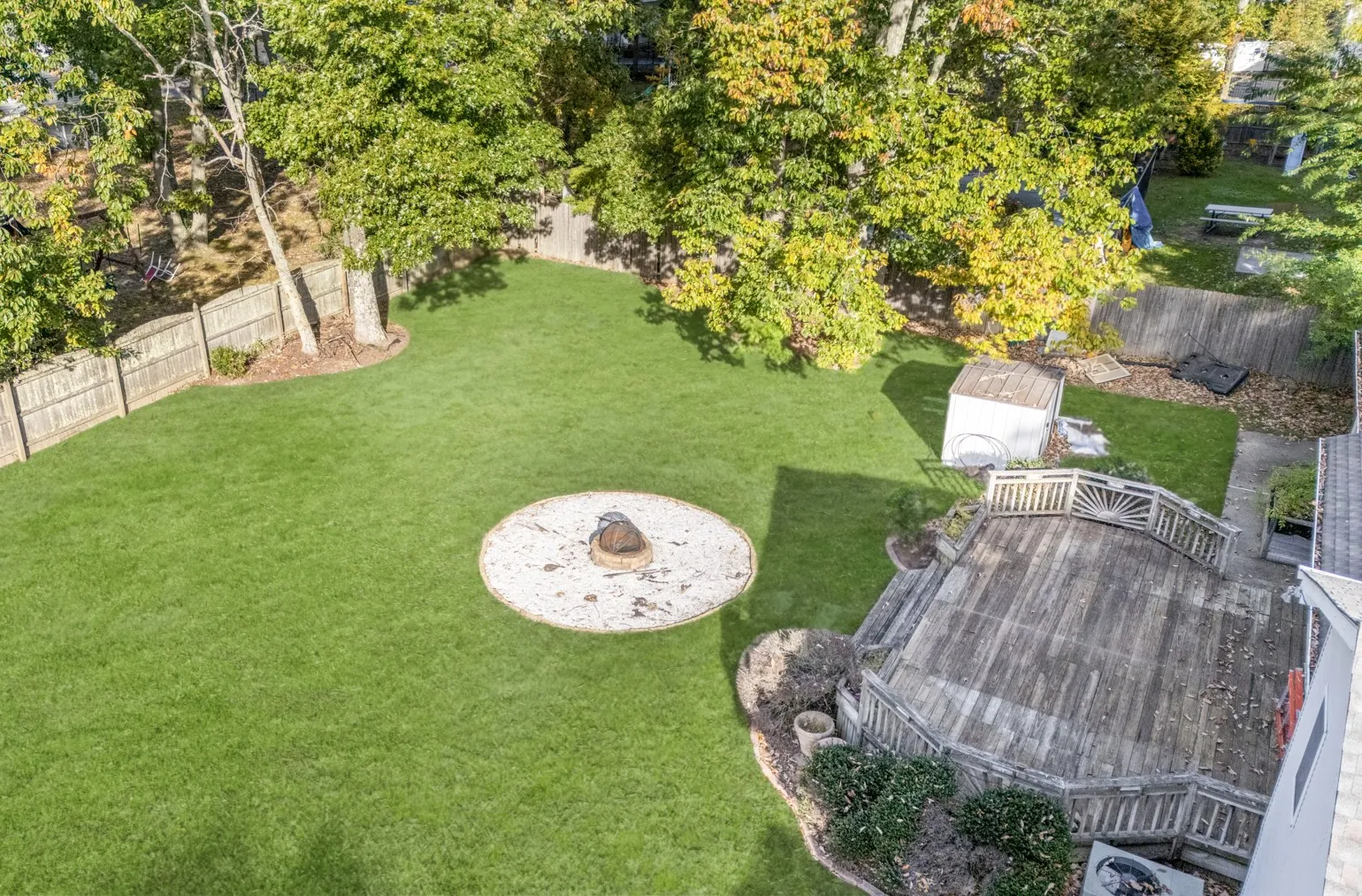 Aerial view of the lawn, deck and mature trees behind the home