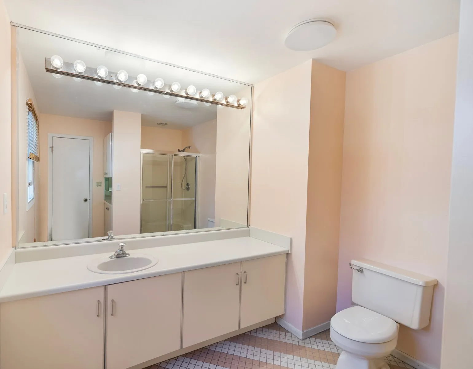 Bathroom with a long vanity, wide mirror and a glass shower