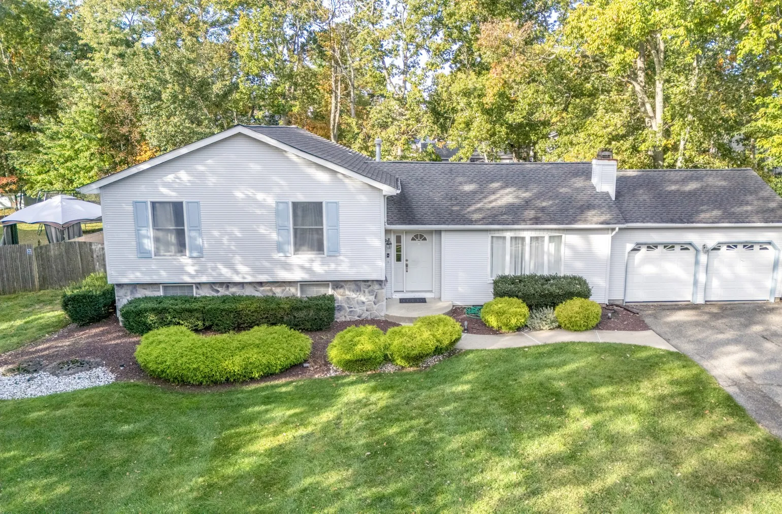 Split-level front exterior with landscaped shrubs and an attached garage