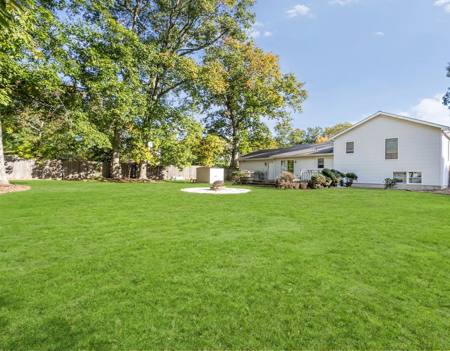 Open green lawn framed by mature trees, with the house in the distance
